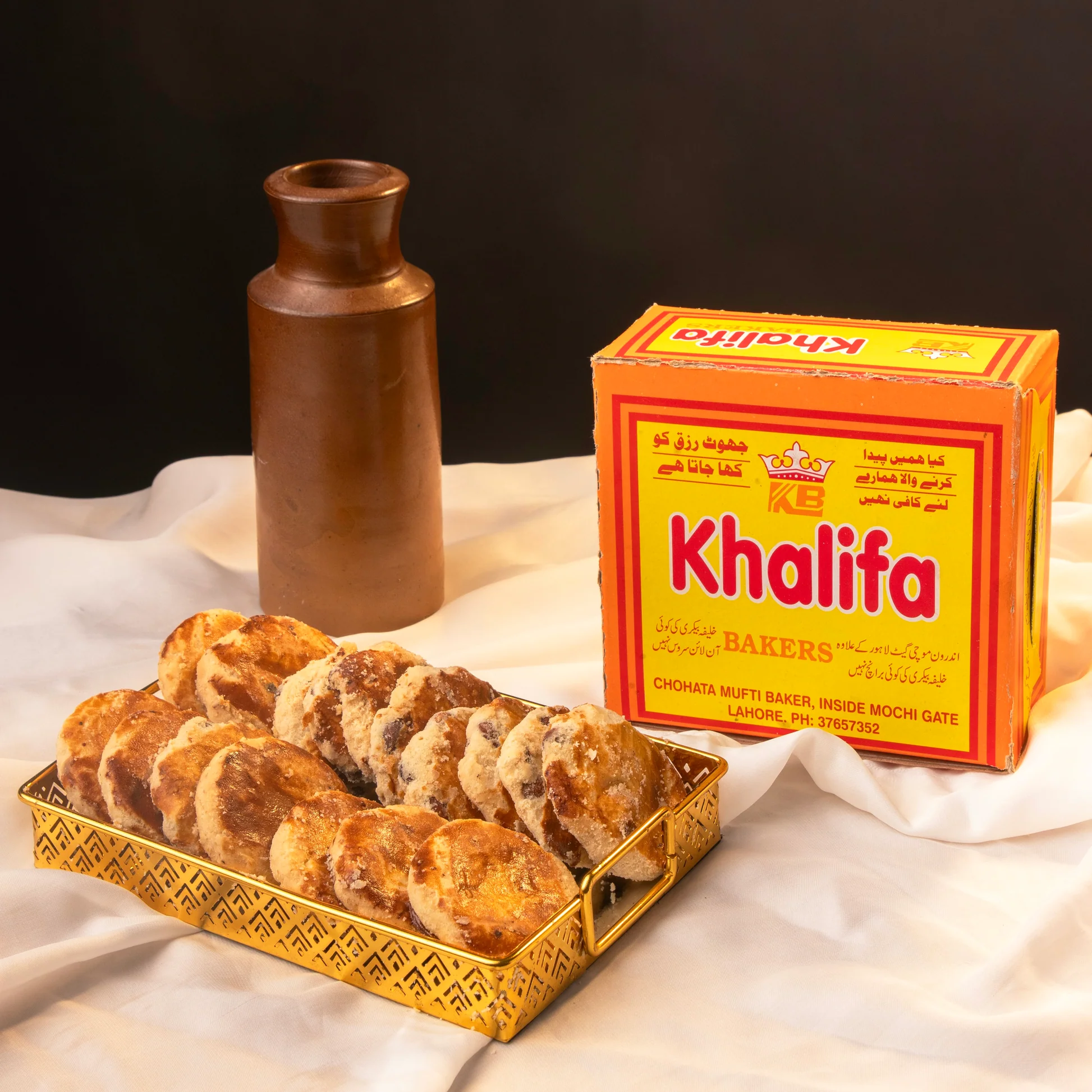 Golden tray of freshly baked Khalifa nan khatai beside a clay pot